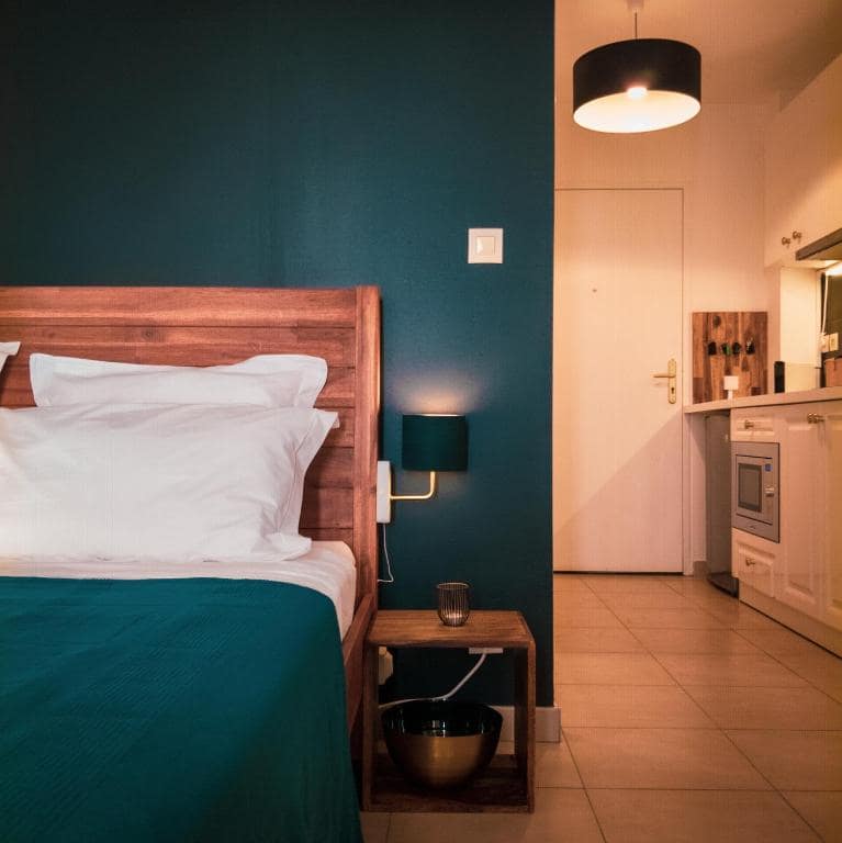 Chambre avec mur bleu canard et tête de lit en bois · © Bleu Nuit